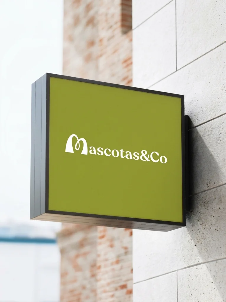 Letrero verde de Mascotas & Co en una fachada de piedra